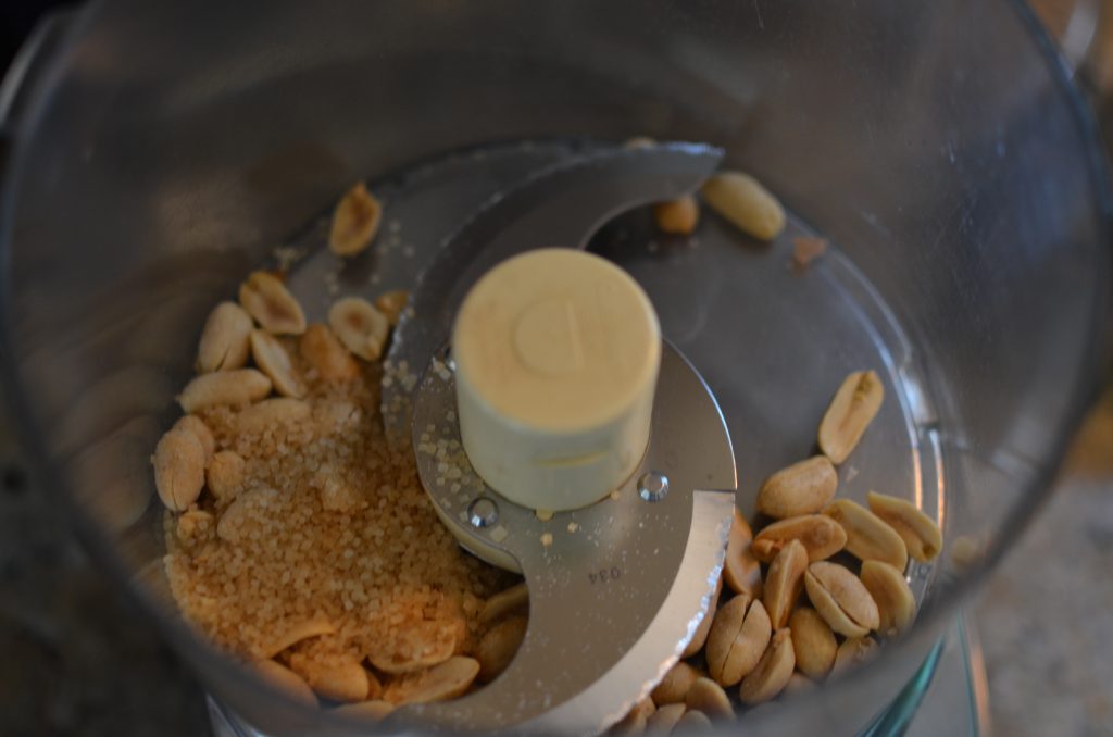 A picture of peanuts and sugar in the food processor.
