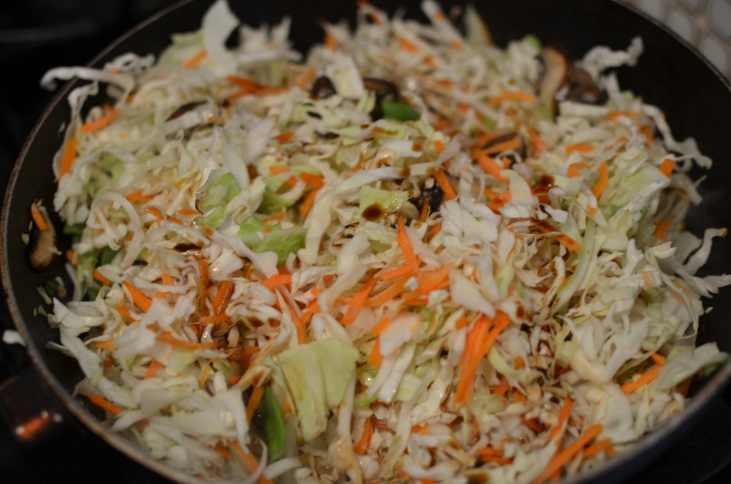 Cole slaw mix added to the wok with soy sauce and celery seed.